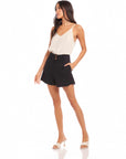 Woman wearing black Cece Pleated Trouser Shorts with white sleeveless top and heels