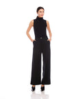 Woman wearing black Mina High Waist Pants with wide leg and front pleats, styled with sleeveless black top and black heels.