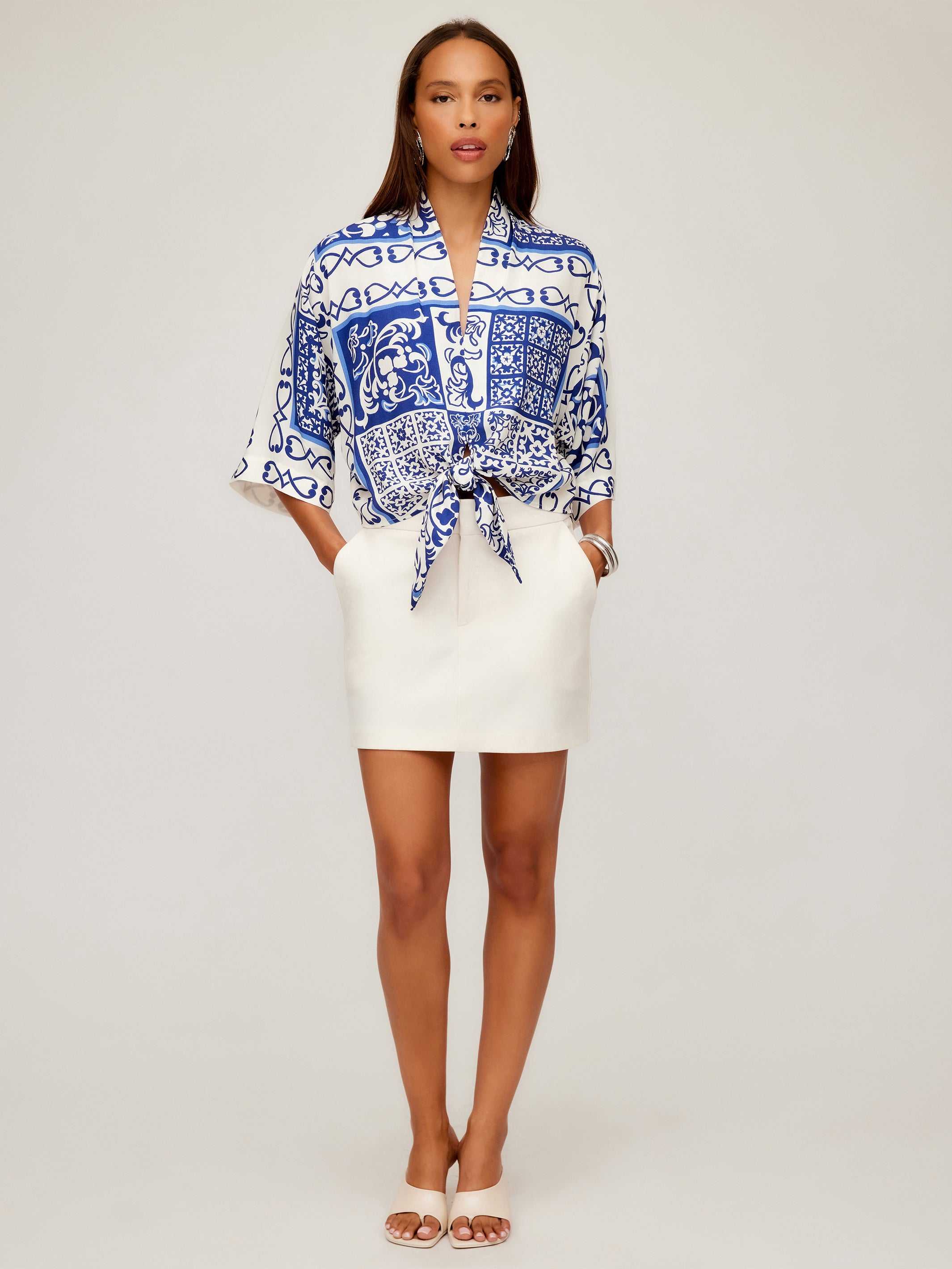 Woman wearing Maribel Modern Skirt white pencil silhouette with side pockets and blue patterned tied blouse