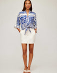 Woman wearing Maribel Modern Skirt white pencil silhouette with side pockets and blue patterned tied blouse