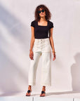 Woman wearing black Mindy T-Shirt with square neck and short sleeves paired with white pants and sunglasses outdoors