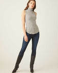 Woman wearing grey sleeveless turtleneck slim fit rib-knit top with shirttail hem and dark skinny jeans