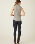 Woman wearing grey sleeveless turtleneck top with shirttail hem paired with dark jeans and black boots, back view