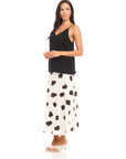 Woman wearing black Carys Silk Cami with adjustable spaghetti straps and V-neckline paired with white patterned midi skirt.