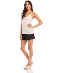 Woman wearing white Carys Silk Cami with adjustable spaghetti straps and black shorts