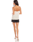 Woman wearing white Carys Silk Cami with adjustable spaghetti straps and black shorts, viewed from the back