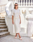 Woman wearing a white Lori Midi Skirt with front buttons and slit, styled with matching top and sunglasses in an outdoor setting