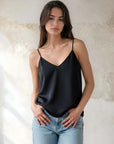 Woman wearing black Carys Silk Cami with adjustable spaghetti straps and V-neckline paired with jeans