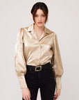 woman wearing gold crushed metallic long sleeve button up shirt with notched collar and shell buttons