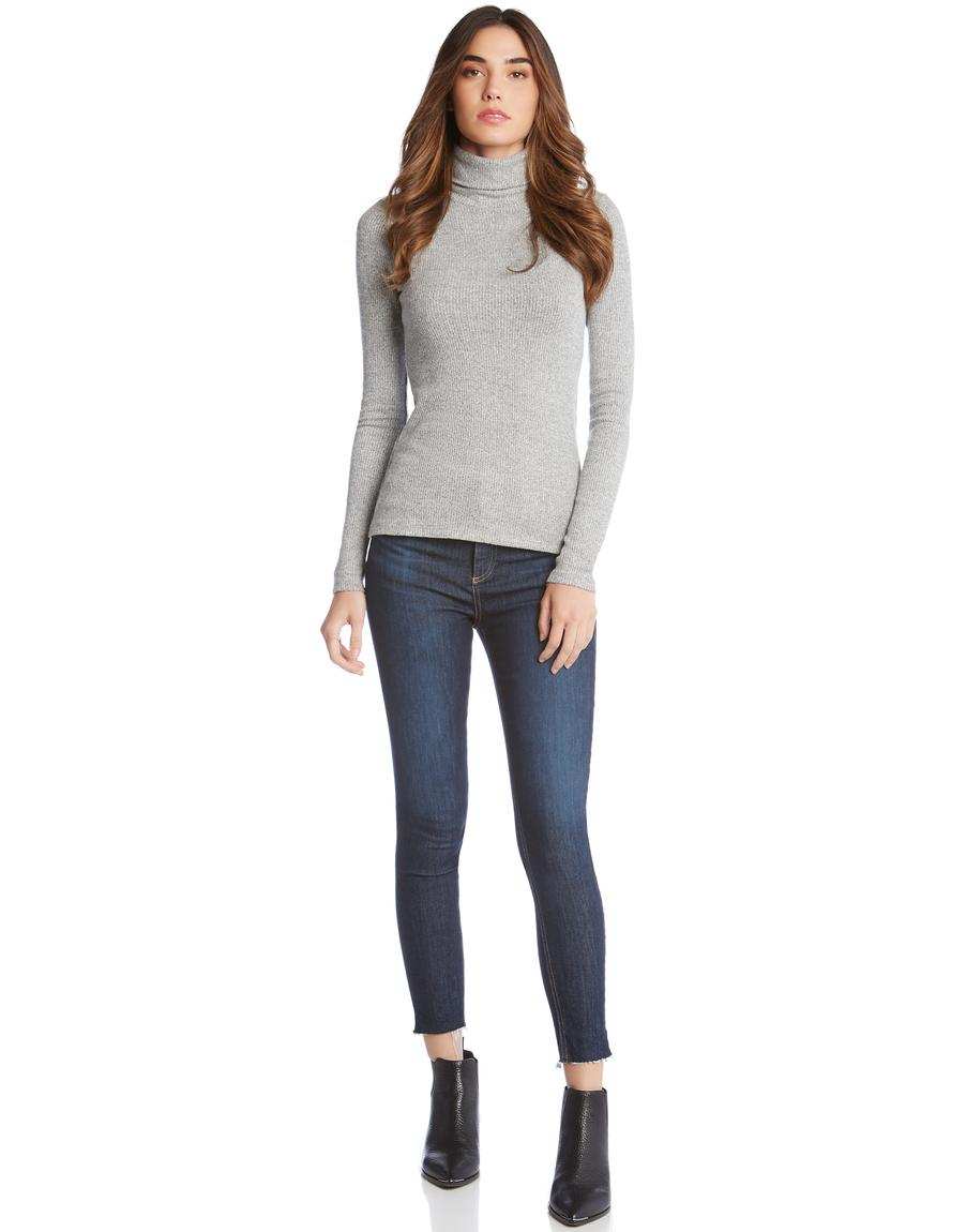 Woman wearing a gray long sleeve turtleneck paired with dark skinny jeans and black ankle boots