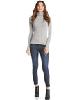 Woman wearing a gray long sleeve turtleneck paired with dark skinny jeans and black ankle boots