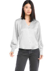 Woman wearing white satin tie back top with long cuffed sleeves and V-neck button down