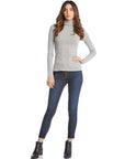 Woman wearing a gray long sleeve turtleneck sweater paired with dark skinny jeans and black ankle boots