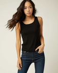Woman wearing black everyday rib tank top with scoop neck and sleeveless design paired with blue jeans