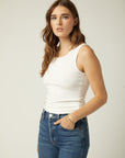 Woman wearing white sleeveless Everyday Rib Tank with scoop neck and straight hem paired with blue jeans.