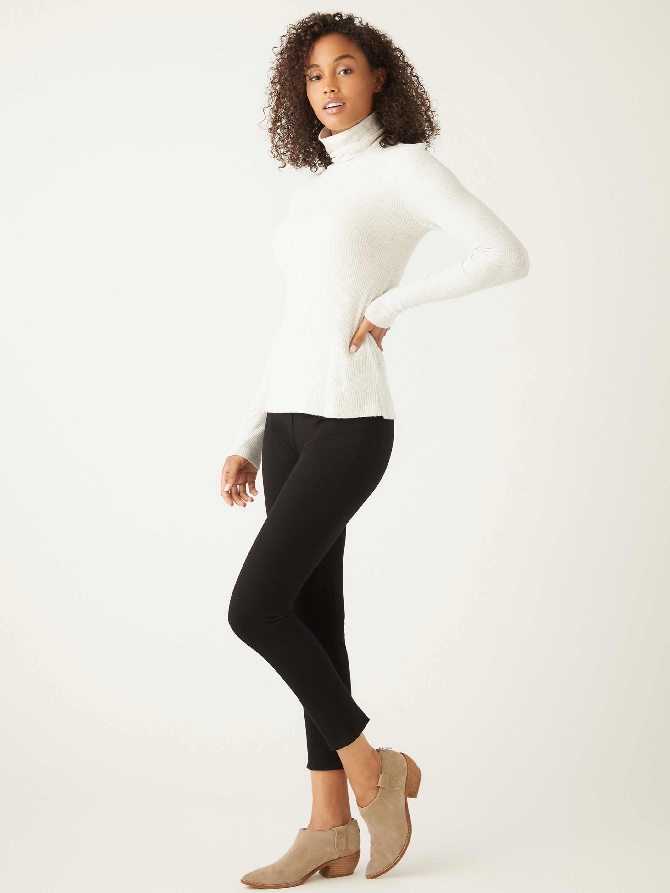 Woman wearing white brushed rib-knit long sleeve turtleneck with black pants and beige ankle boots