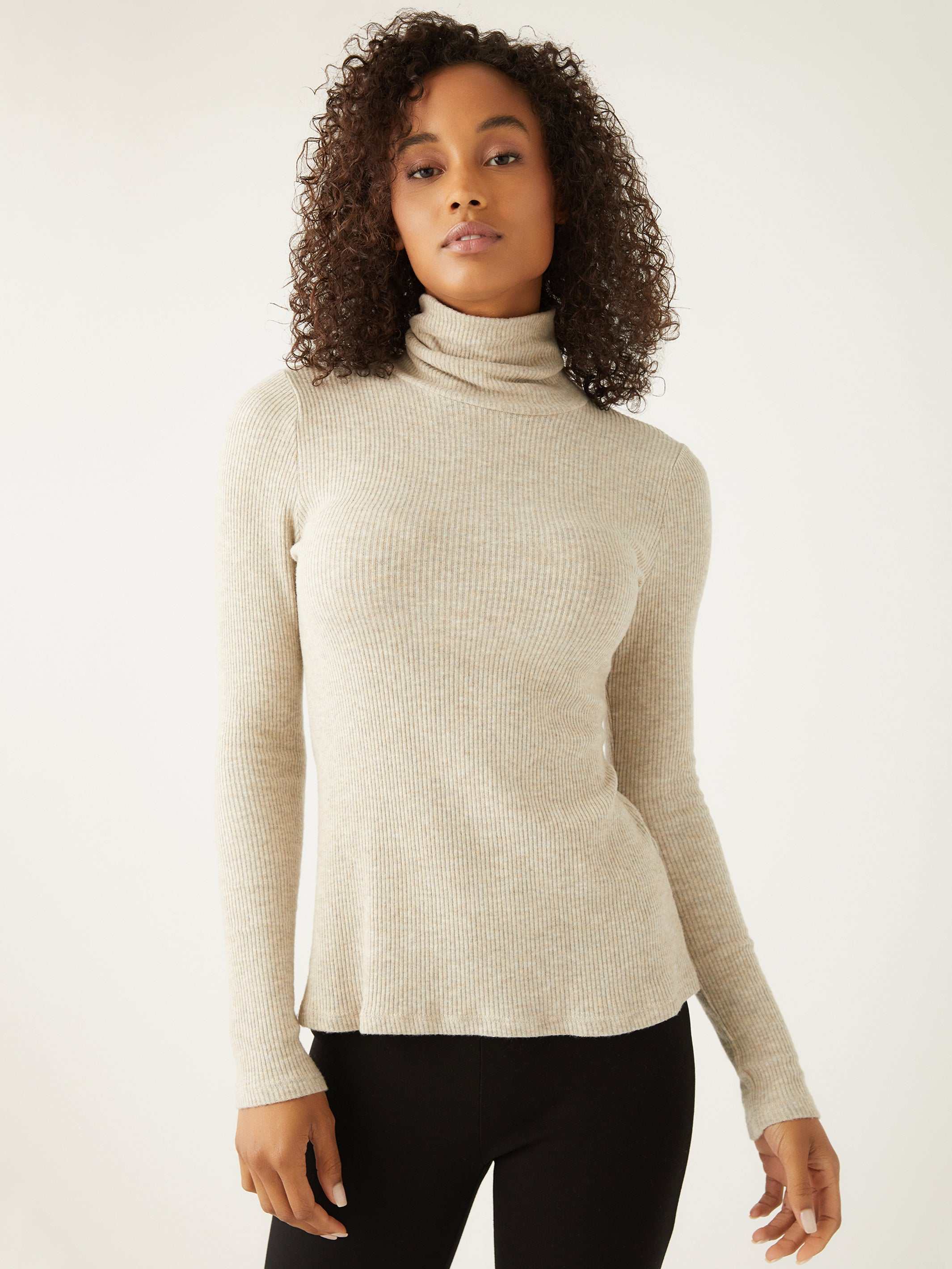 Woman wearing beige brushed rib-knit long sleeve turtleneck top with straight hem