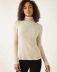 Woman wearing beige brushed rib-knit long sleeve turtleneck top with straight hem