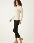 Woman wearing beige long sleeve turtleneck paired with black pants and beige ankle boots