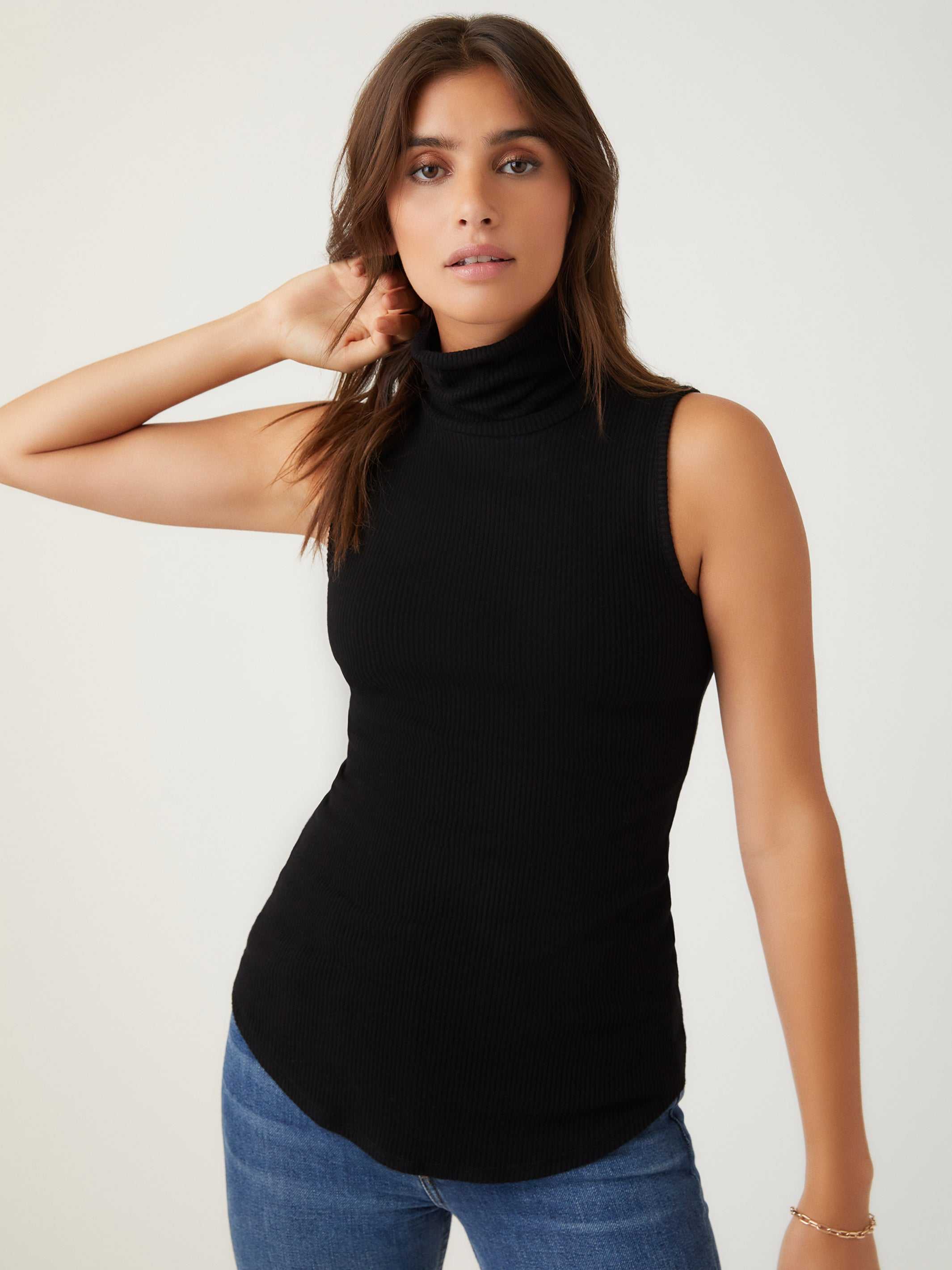 Woman wearing black sleeveless turtleneck slim-fit rib-knit top with shirttail hem