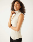 Woman wearing a slim fit beige sleeveless turtleneck rib-knit top with shirttail hem