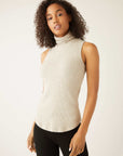 Woman wearing a beige sleeveless rib-knit turtleneck top with a slim fit and shirttail hem