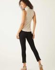 Woman wearing a slim fit sleeveless turtleneck top paired with black pants and ankle boots, back view