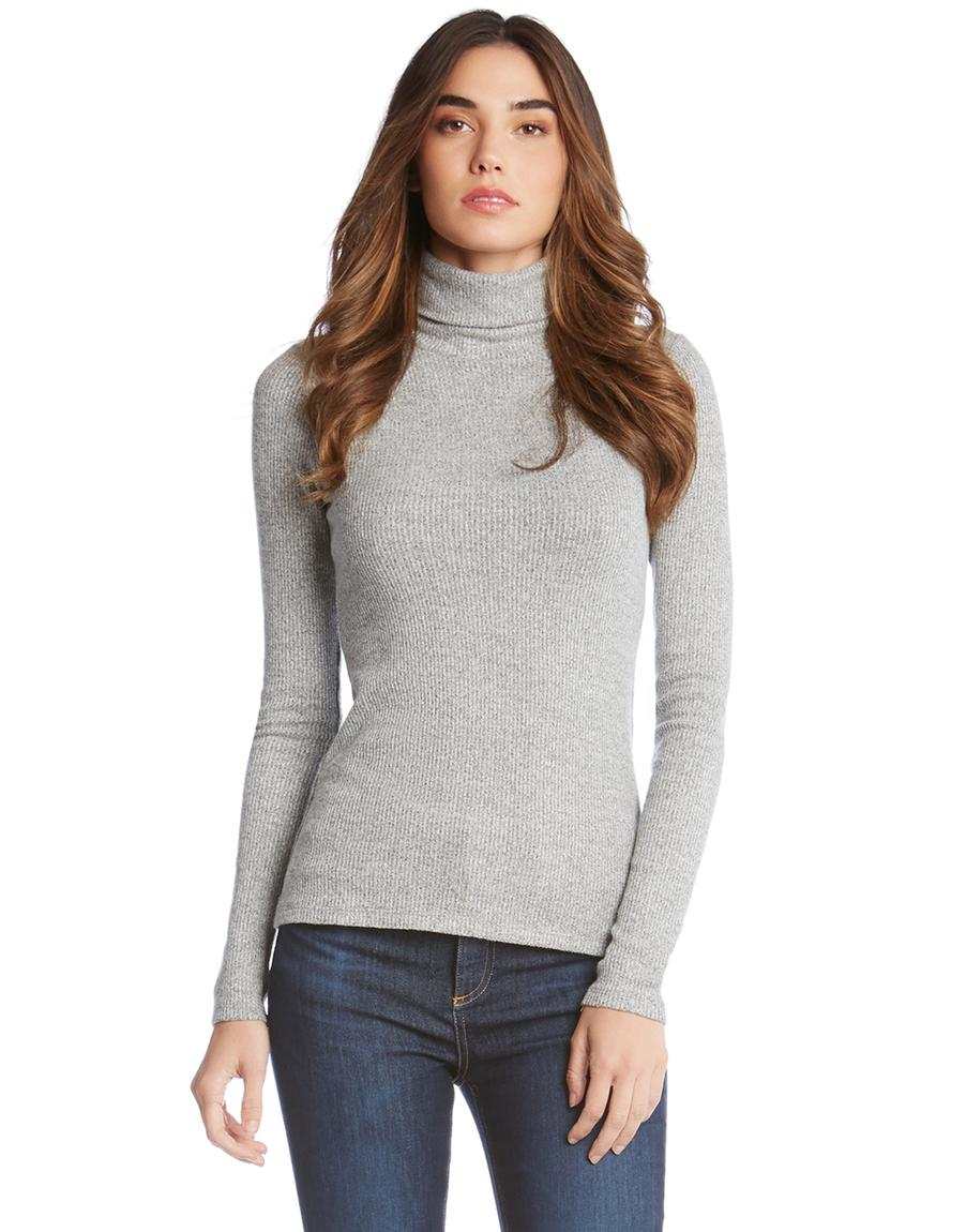 Woman wearing a gray long sleeve turtleneck rib-knit sweater paired with dark jeans