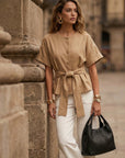Woman wearing Kai Belted Button-Up Top with short cuffed sleeves and waist tie