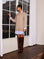 Woman wearing Carrie Mixed Media Dress with wheat sweater overlay and white with blue striped shirttail hem, paired with brown knee-high boots.