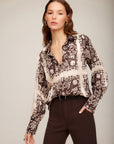 Woman wearing Tess Half Placket Shirt with earthy block print, relaxed collar, long buttoned sleeves, and V-neckline, styled with dark pants.