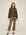 Woman wearing olive green Sigourney Pintuck Pants with cropped flare and elastic waistband paired with matching hoodie