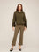 Woman wearing olive green Sigourney Pintuck Pants with cropped flare and elastic waistband paired with matching hoodie