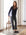 Woman wearing navy Celine Mixed Media cardigan with white and blue stripe panels, paired with black cuffed pants and black flats, standing indoors next to a wooden chair