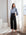 Woman wearing blue Alana Keyhole Top with knotted neckline and black wide-leg trousers in bright room