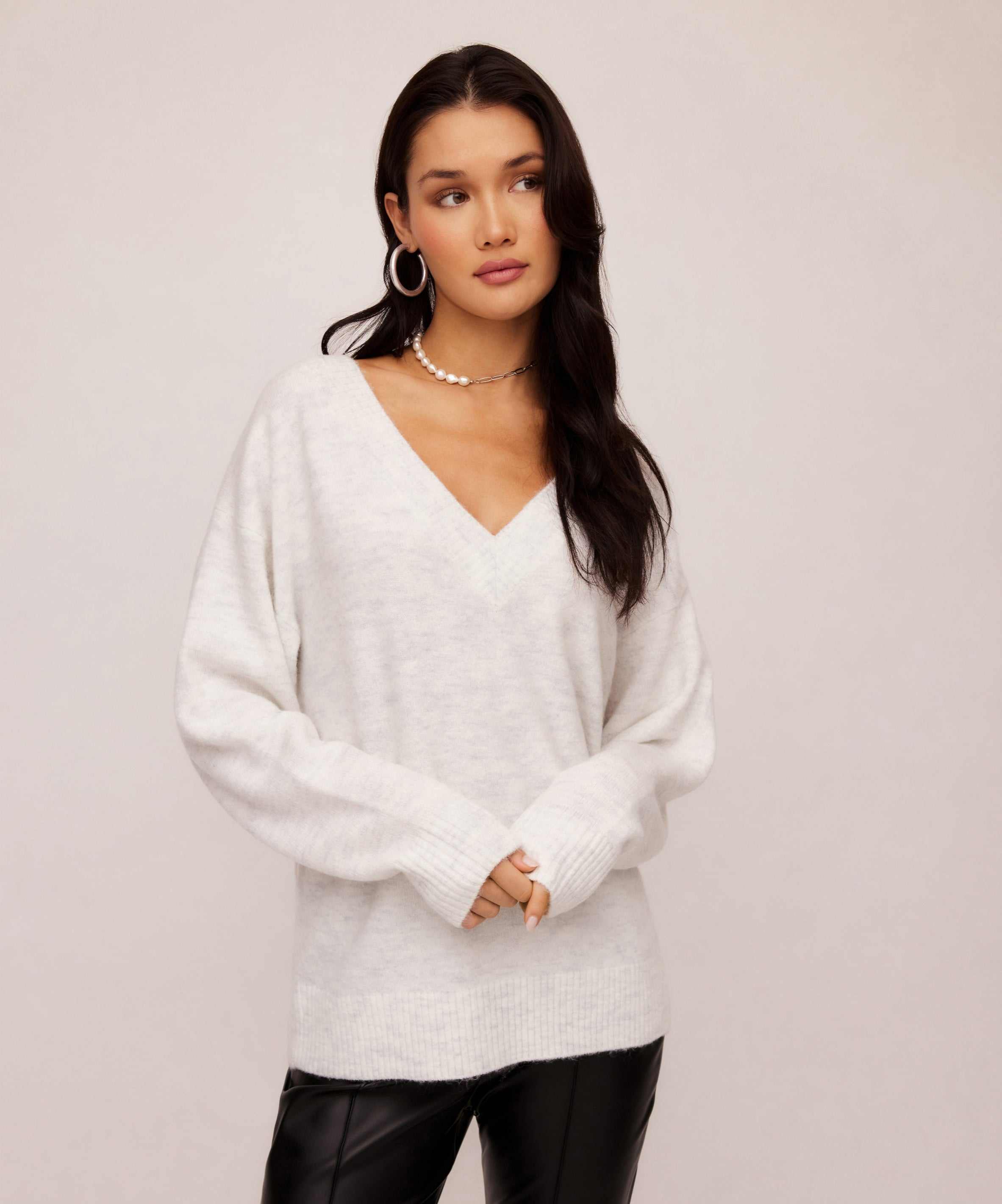 Woman wearing ash light heather gray Deliana Oversized Sweater with V-neck and ribbed cuffs paired with black pants