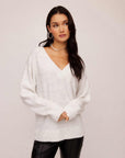 Woman wearing ash light heather gray Deliana Oversized Sweater with V-neck and ribbed cuffs paired with black pants